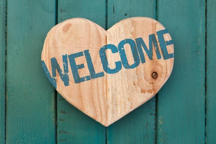 welcome message on wooden carved heart turquoise painted background 