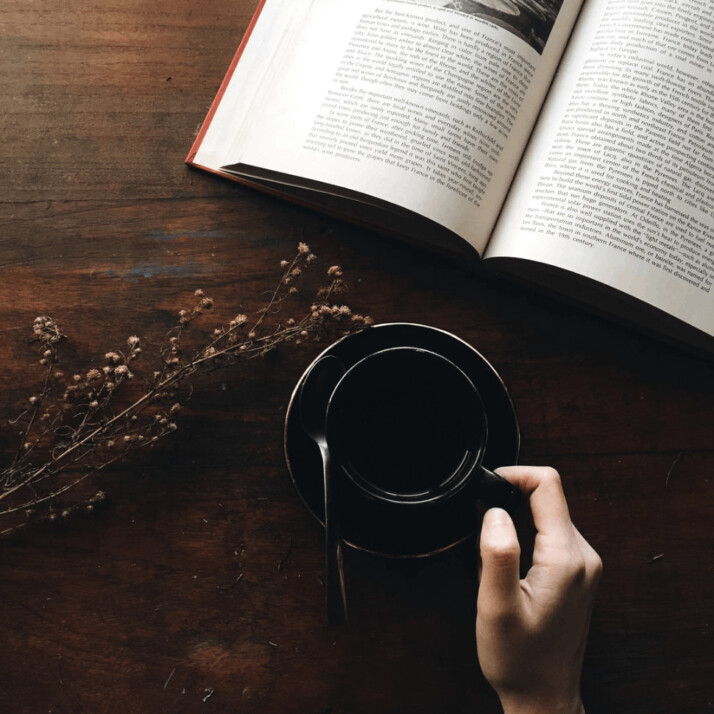 round black metal container and white open book on brown table