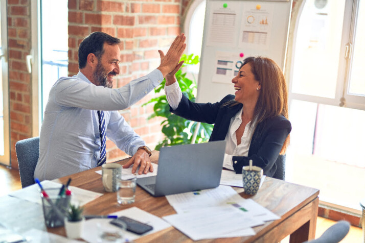 Two people laughing and giving each other a high five.