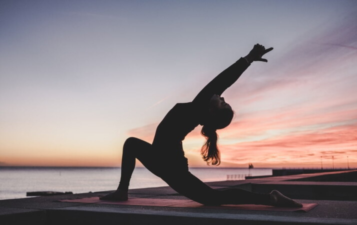 Silhouette photography of a woman doing yoga on a beach.