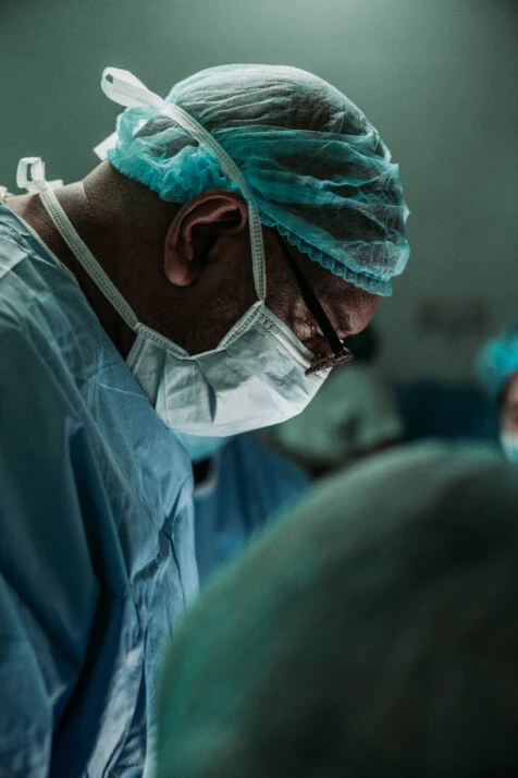 a surgeon in the operating theatre focusing on his patient.