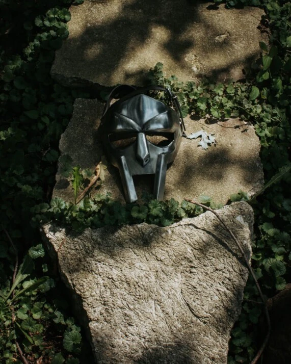 mask of metal face doom on top of a rock and some leaves.