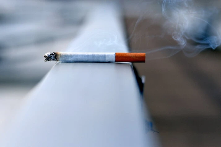 A burning cigarette with a bit of ash on its tip.