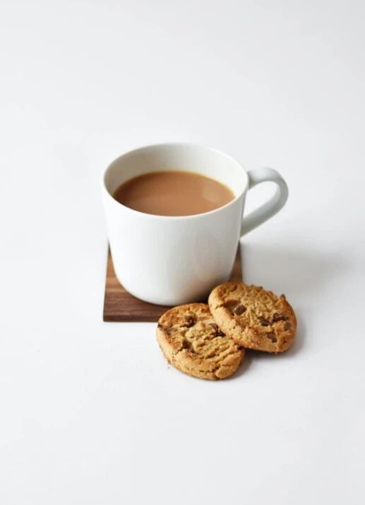 tea with milk in a white mug and two biscuits.