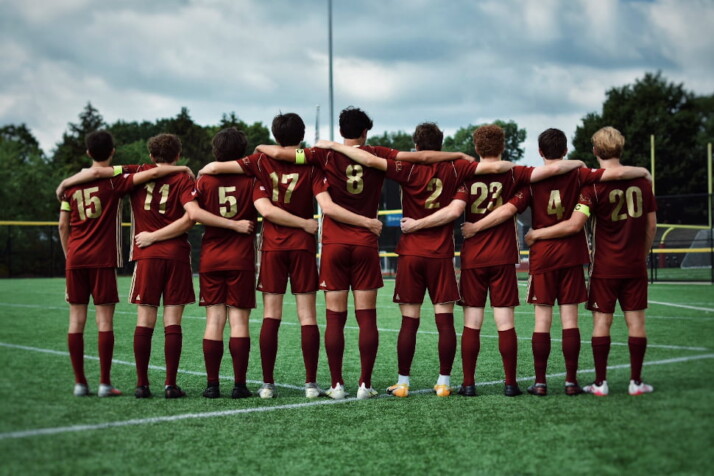 A sports team wearing red uniforms standing together on a field.