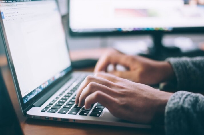 A person typing something on a laptop using both hands.