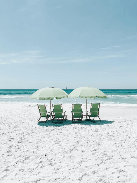 green chairs under umbrellas on shore close to ocean
