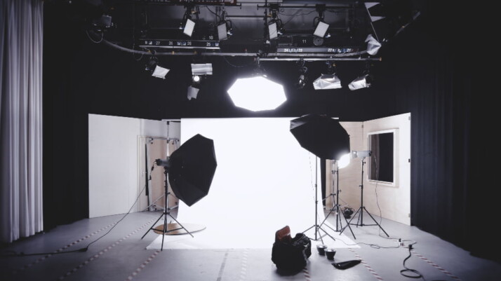 A brightly lit photo studio, with a white screen in the background.