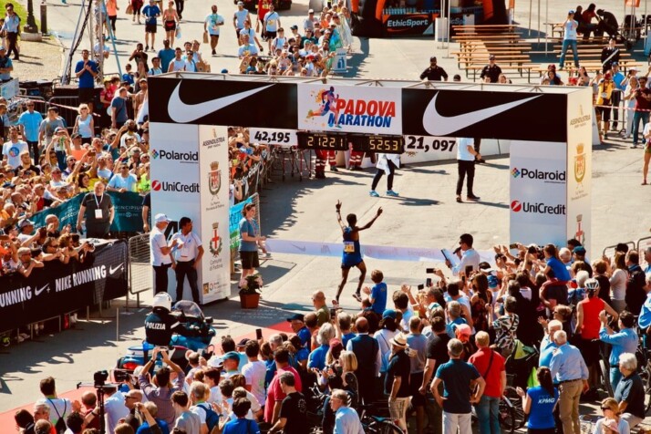 A crowd watches a Padova marathoner run past the finish line.