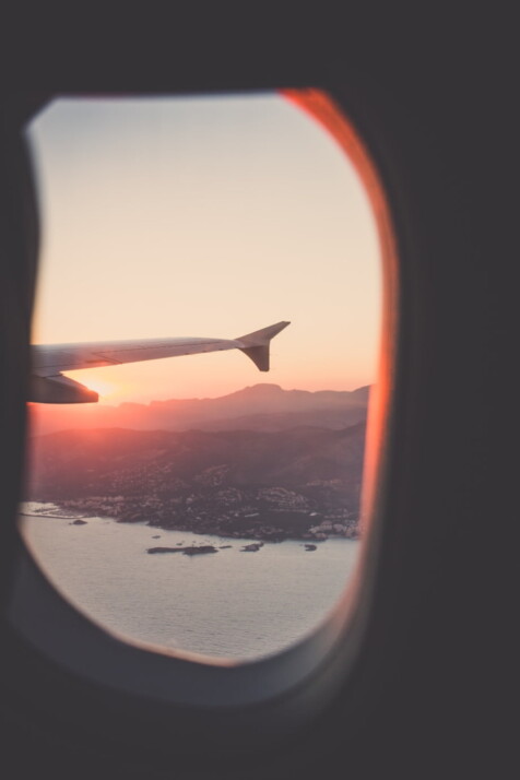 photo from a plane window of a city on the coast during sunset.