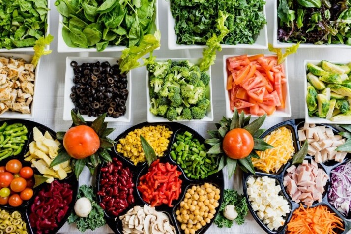 A wide angle shot of a buffet of green, yellow, and red vegetables