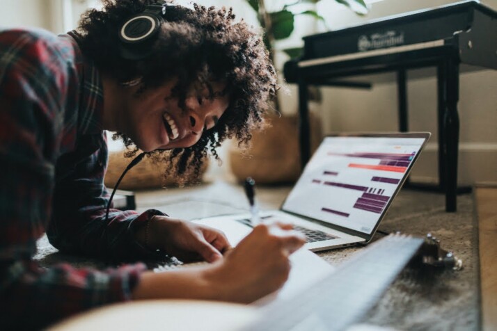 A young black woman writing songs while listening to music