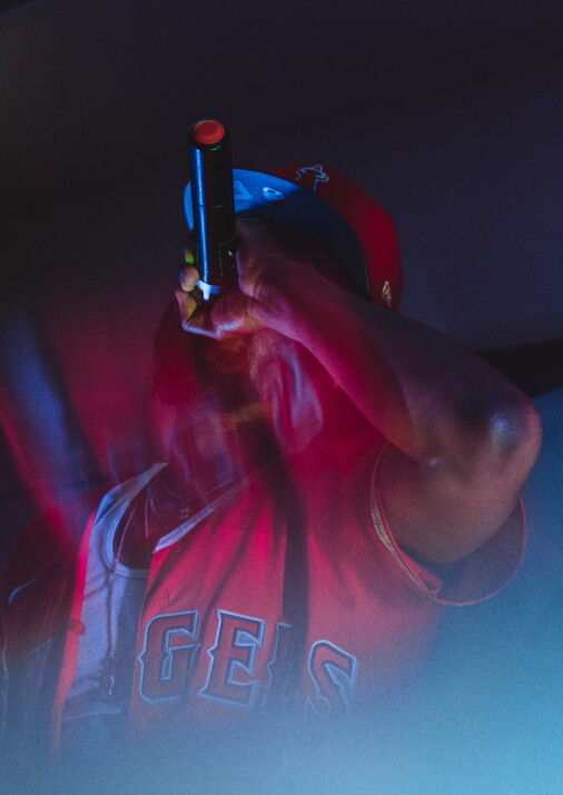 A black rapper wearing a red jersey and white tank top shouting at the microphone