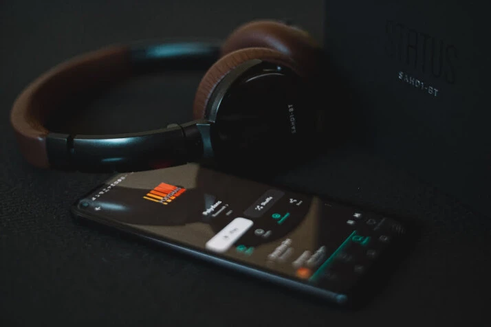 A black headset wirelessly connected to a phone playing some songs.