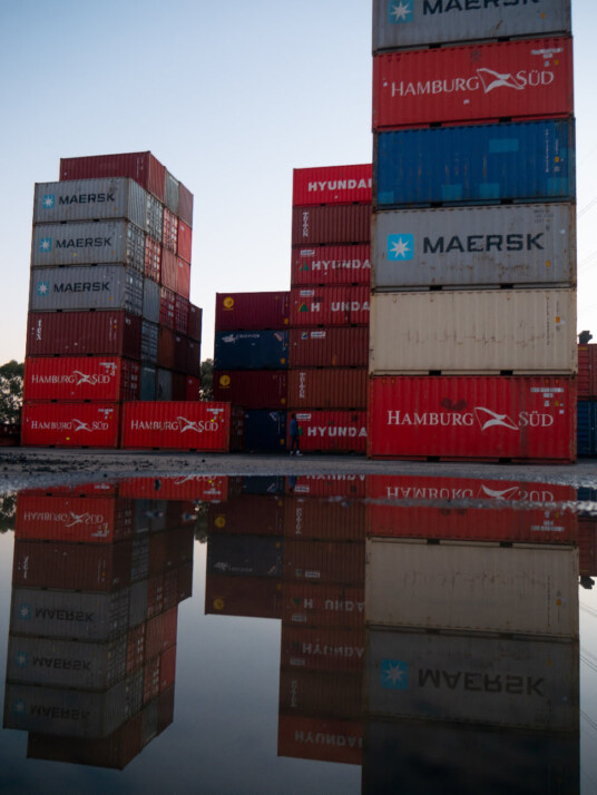 Photo of shipping containers stacked on top of one another.