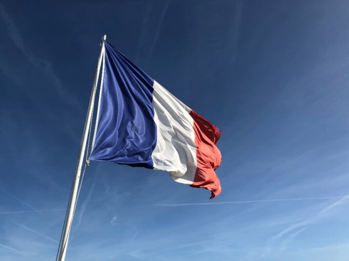 A picture of a French flag waving in the wind. 