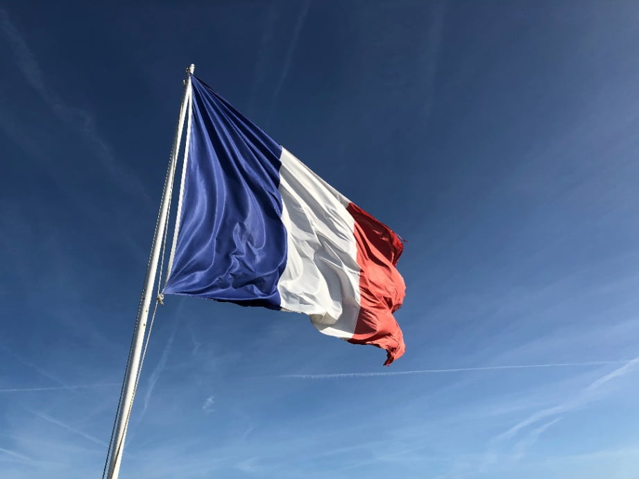 A picture of a French flag waving in the wind.