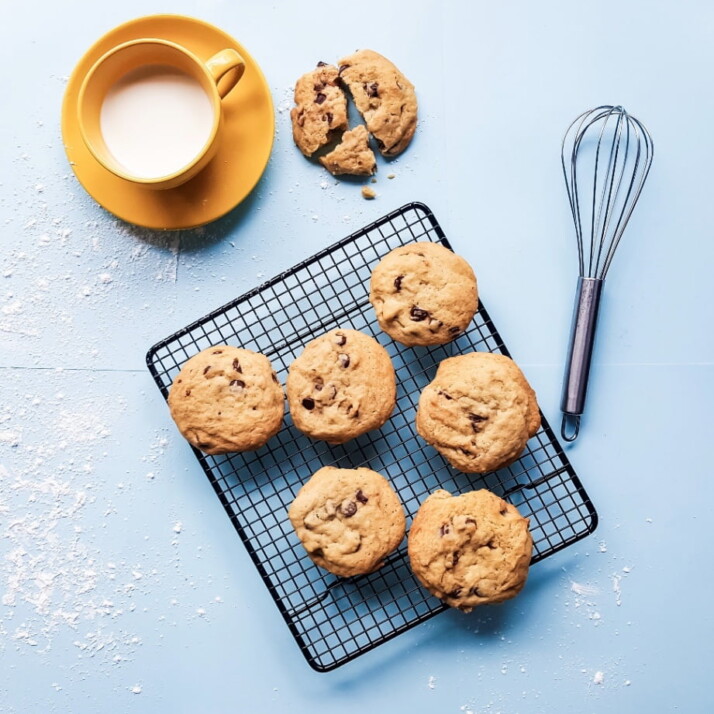Cookies placed next to a whisk and a cup of milk.