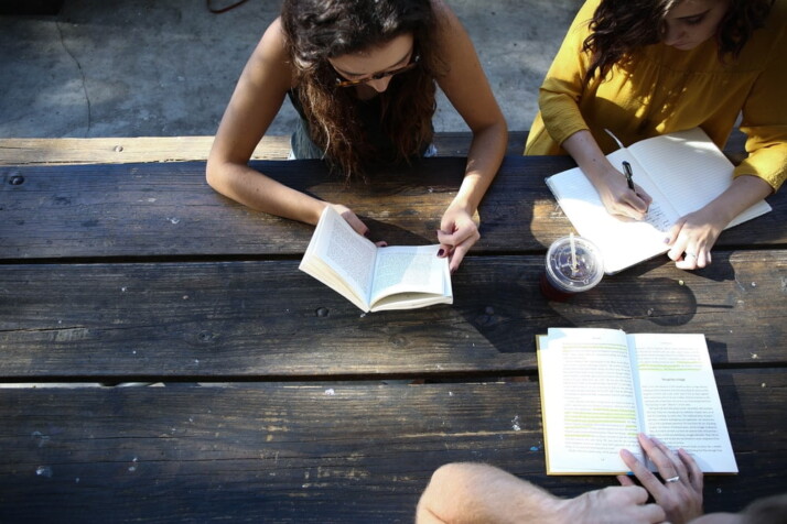 People sitting together at a table, reading their books.