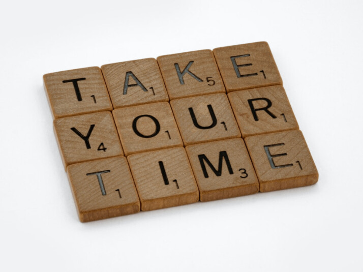 TAKE YOUR TIME brown wooden blocks on a white surface.