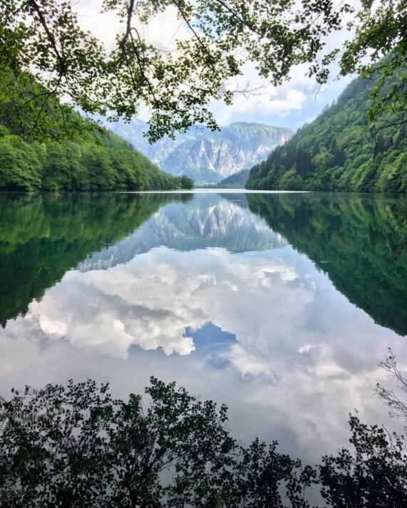 A lake in a valley surrounded by green trees.