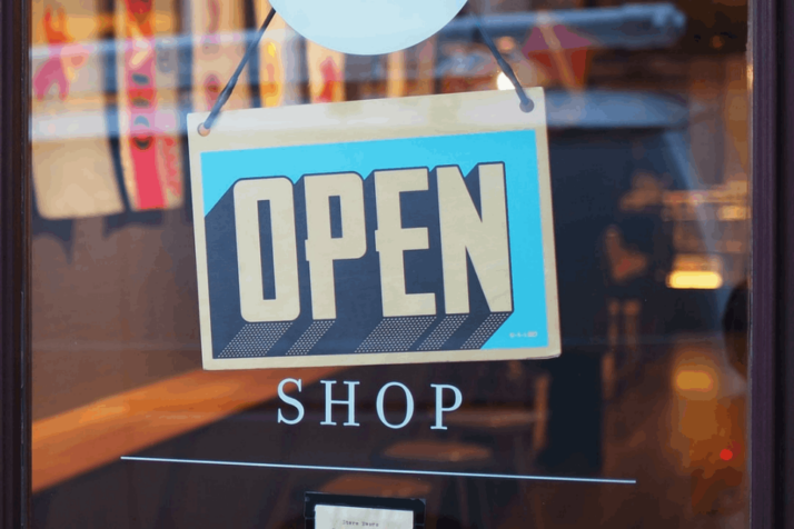 An blue and yellow open signage hanging from the door.