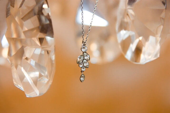 A pair of clear gemstones flanking a silver-colored pendant necklace.