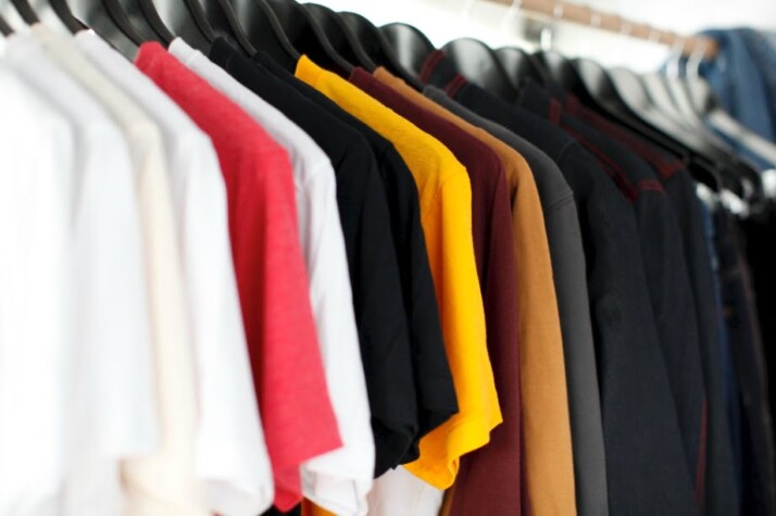 Colorful t-shirts and other clothing hung on shelves in the market.