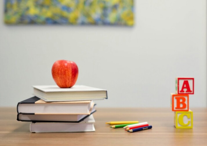 A pile of books with an apple on top, next to alphabet blocks.