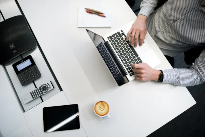 A man working on a laptop with a coffee on the table.