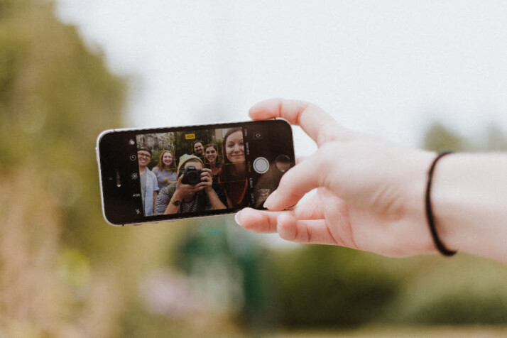 A group of friend taking a selfie using an iPhone.