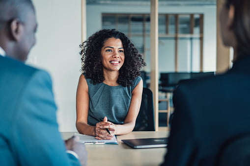 three people sitting round a table talking in the office 