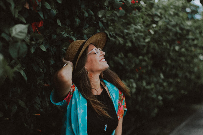 A girl in a blue shirt and brown hat posing for a photo