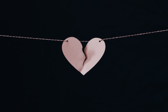 broken heart hanging on wire with black background that looks scary and sad