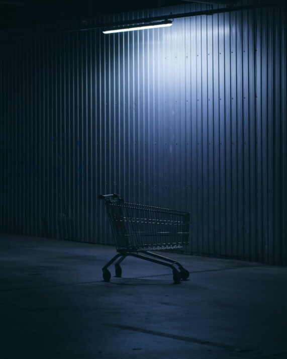 an abandoned shopping cart illuminated by an overhead LED light.