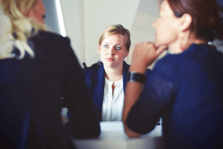 woman wearing blue jacket sitting in front of table opposite two women