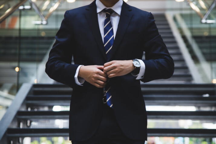 A man wearing a formal suit with a blue tie.