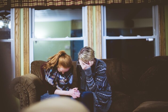 man and woman sitting on sofa in a room grieving