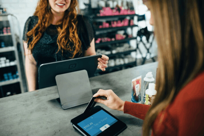 woman holding magnetic card with another woman on a table