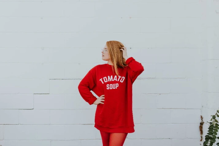 A woman striking a pose dressed in a red sweater and red leggings.