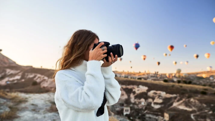 woman wearing white sweater holding camera and taking shots