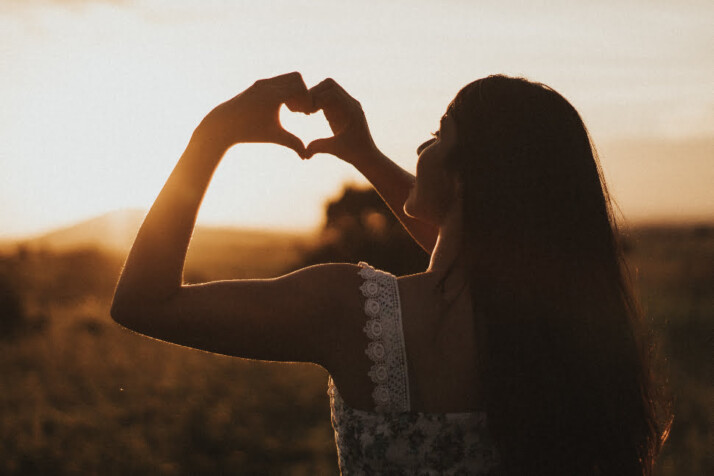 A girl showing heart sign with her hands as a symbol of self-love