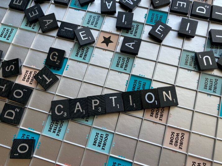 A scrabble board with the word caption in order at the center.