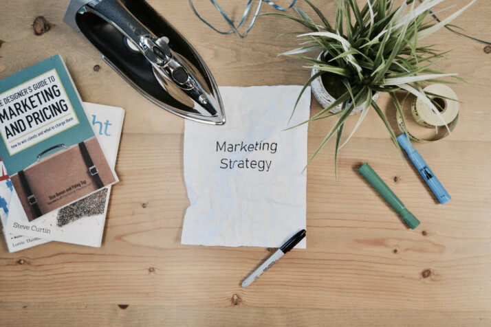 Marketing Strategy text on a white paper placed over a wooden table. 