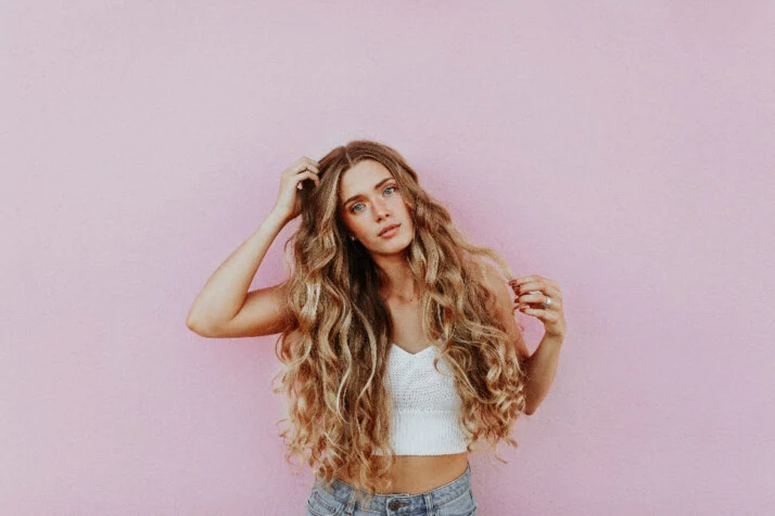 A model with long wavy hair posing for a photoshoot.