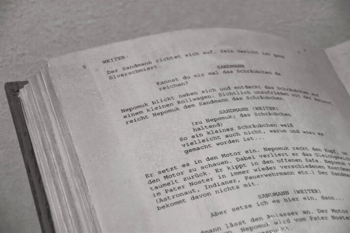 An open screenplay script written on a white paper.