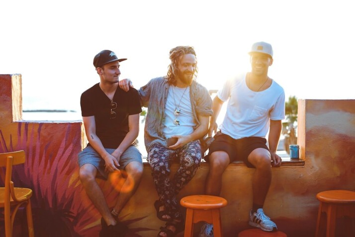 Three men sitting on a wall, having a good time.