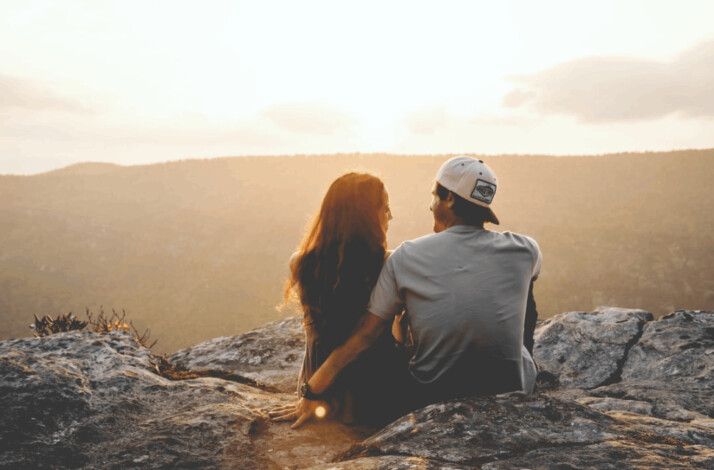 A man and woman sitting on rock during daytime