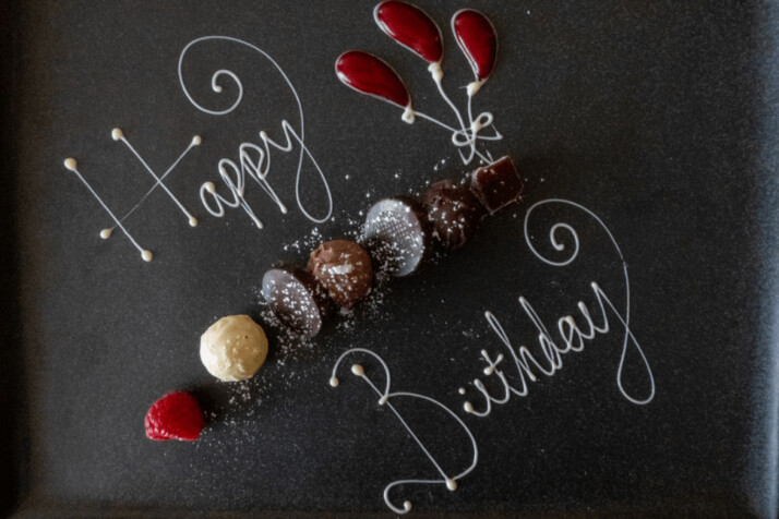 A happy birthday sign written on a black background.