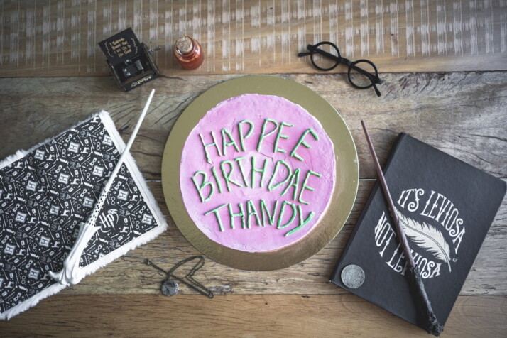 A photo of a birthday cake flanked by Harry Potter themed props.